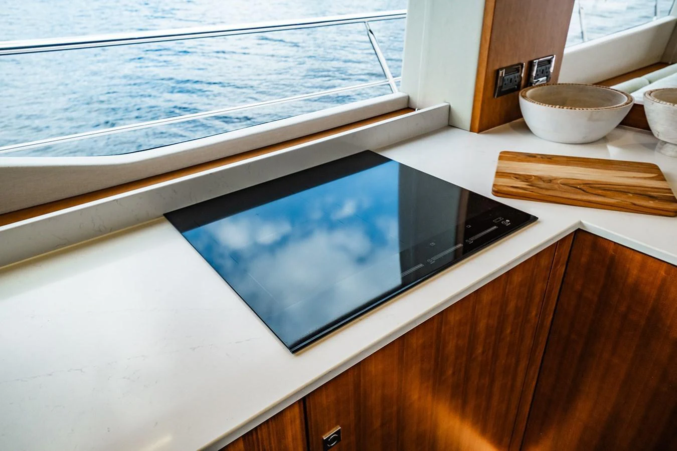The yacht's galley features a sleek induction cooktop with a view of the sea through large windows. aboard INDIGO Yacht for Sale
