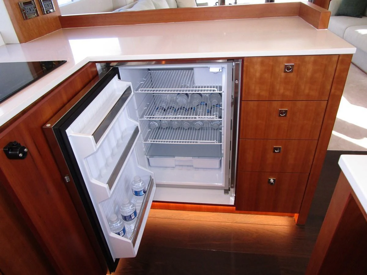 The galley features a compact refrigerator with wooden cabinetry and modern amenities. aboard INDIGO Yacht for Sale