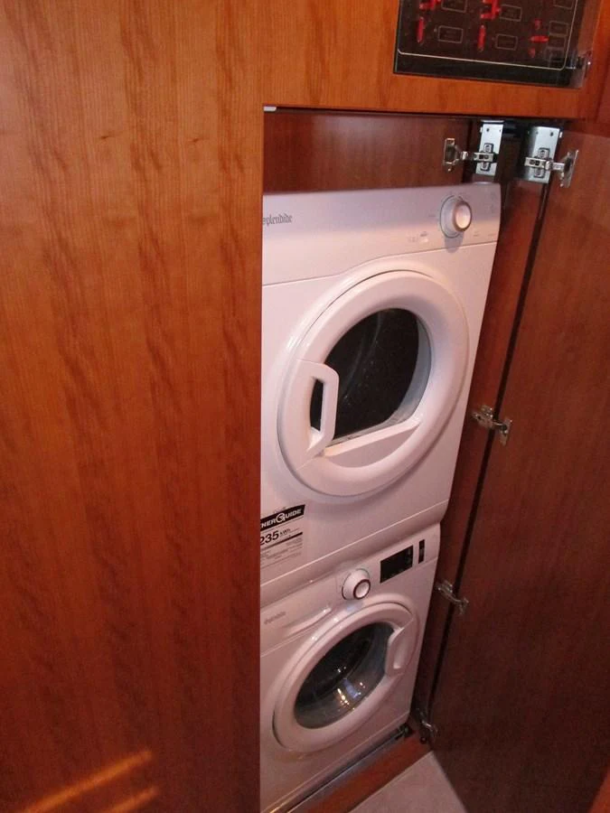 The yacht features a compact and efficient laundry area with a stacked washer and dryer. aboard INDIGO Yacht for Sale