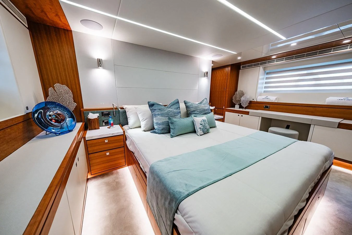 The stateroom features a luxurious bed with elegant bedding and modern lighting. aboard INDIGO Yacht for Sale