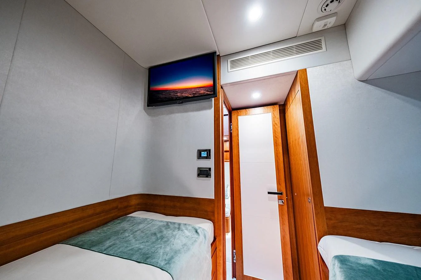 The guest cabin features twin beds, a wall-mounted TV, and a sleek modern design. aboard INDIGO Yacht for Sale