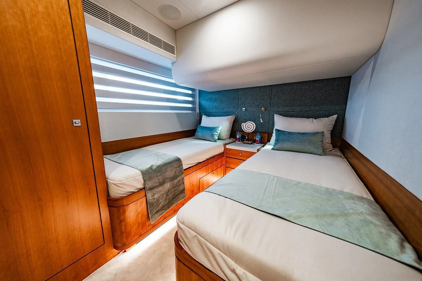 The twin stateroom features two comfortable single beds with elegant wood finishes and soft lighting. aboard INDIGO Yacht for Sale