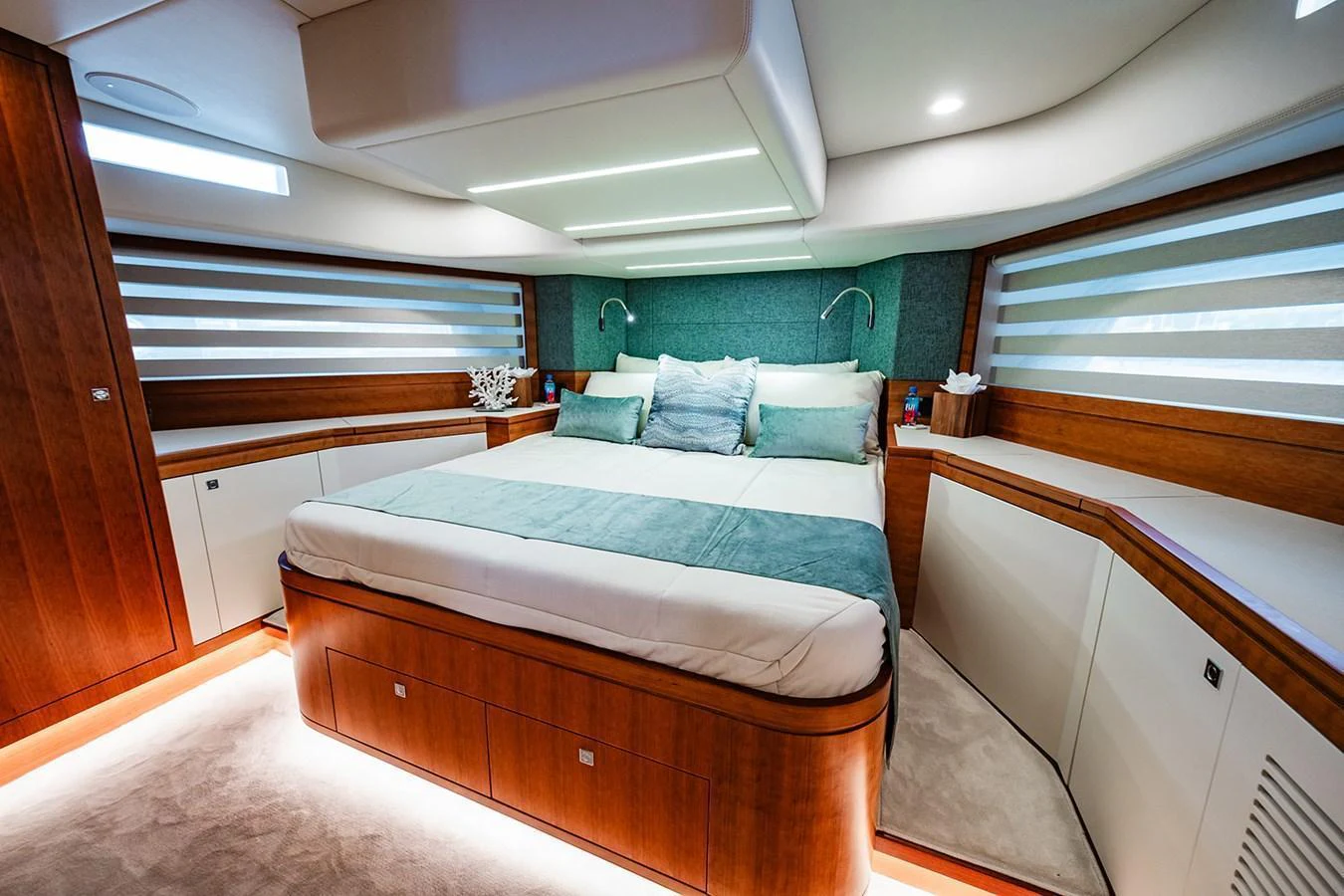 The master stateroom features a luxurious bed with elegant wood finishes and ambient lighting. aboard INDIGO Yacht for Sale