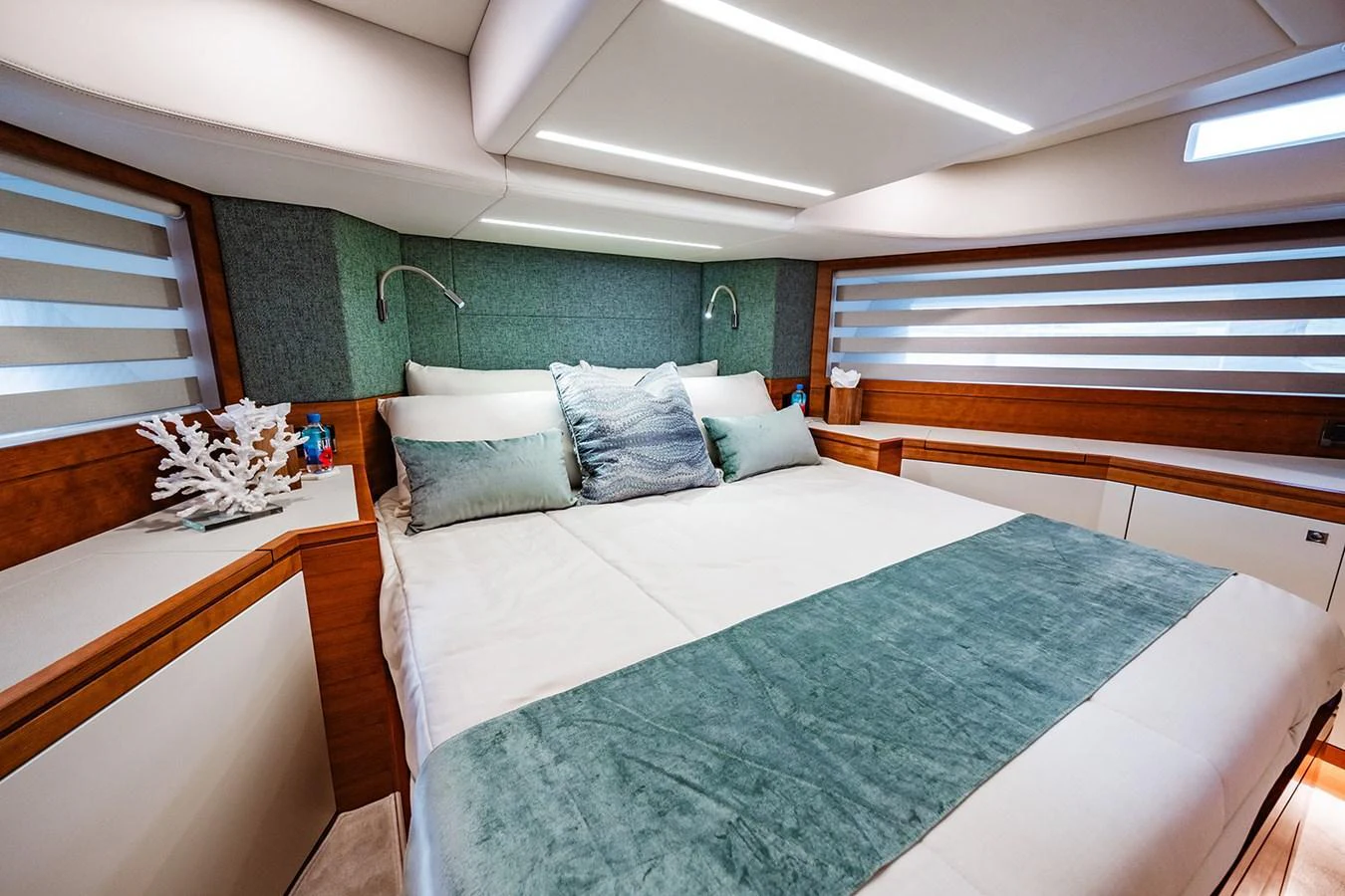 The stateroom features a luxurious bed with elegant bedding and modern lighting. aboard INDIGO Yacht for Sale