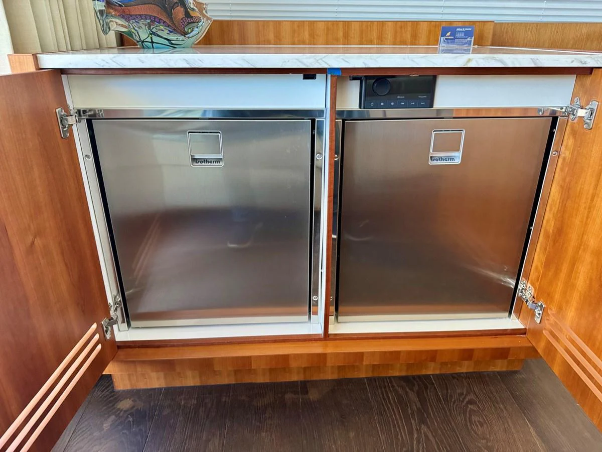 The image showcases a section of the yacht's galley with stainless steel appliances and wooden cabinetry. aboard INDIGO Yacht for Sale