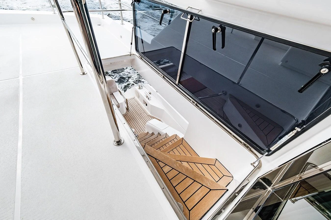 The yacht features a sleek staircase leading from the deck to the interior, with polished metal railings and a view of the water. aboard INDIGO Yacht for Sale