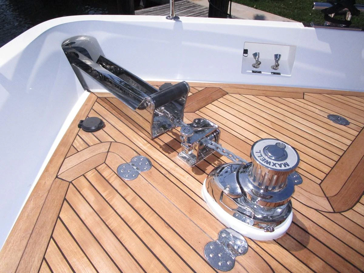The image showcases a polished anchor winch and chain on a teak deck. aboard INDIGO Yacht for Sale