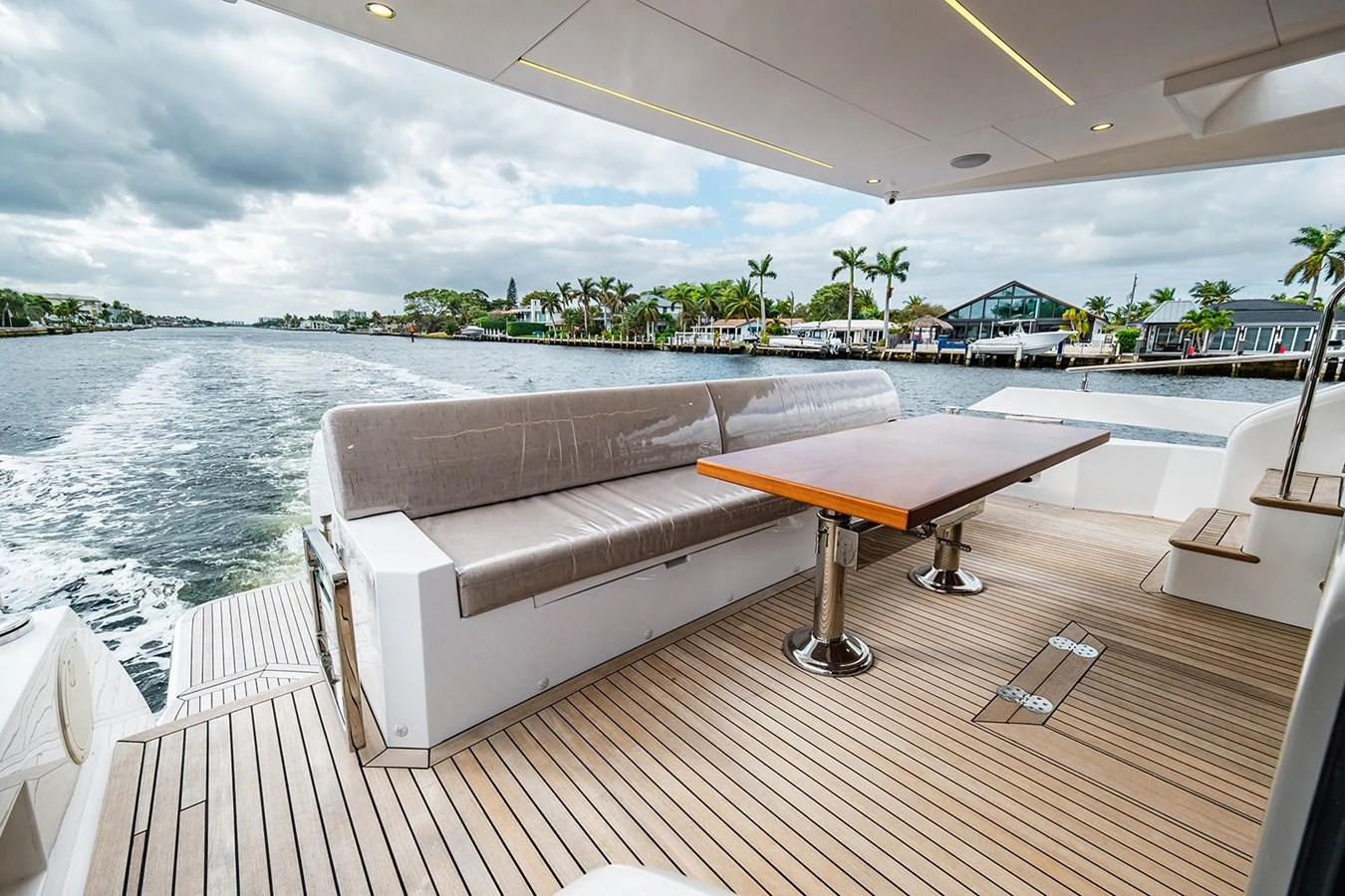 The aft deck features a spacious seating area with a wooden table, perfect for enjoying the view while cruising. aboard INDIGO Yacht for Sale