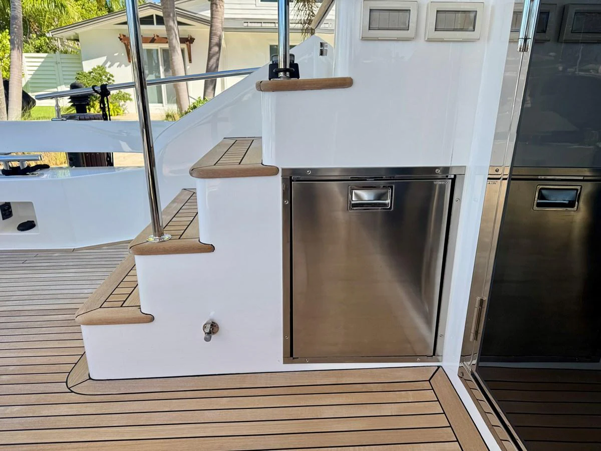 A close-up view of the yacht's deck area featuring a stainless steel storage compartment and stairs. aboard INDIGO Yacht for Sale