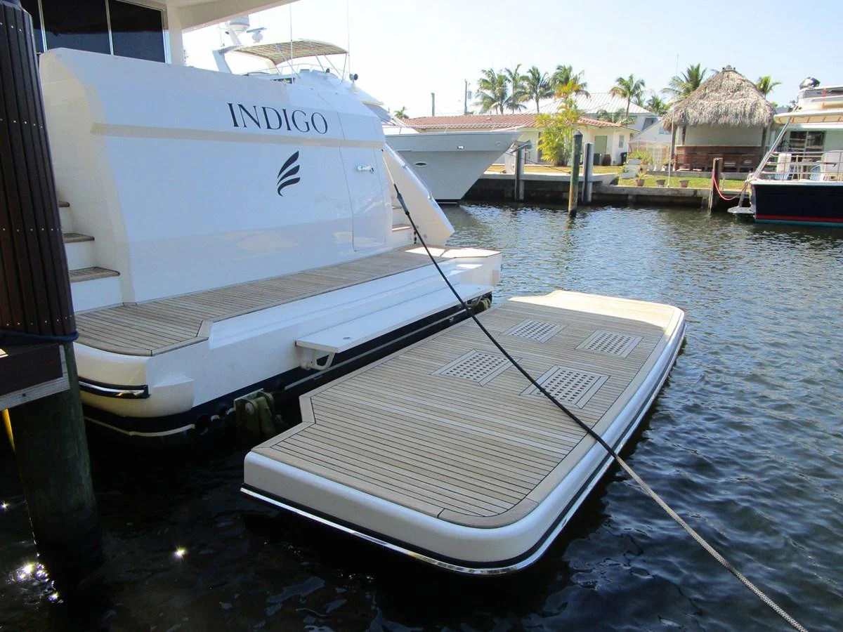 The yacht is docked with a floating platform extending from the stern, providing easy access to the water. aboard INDIGO Yacht for Sale