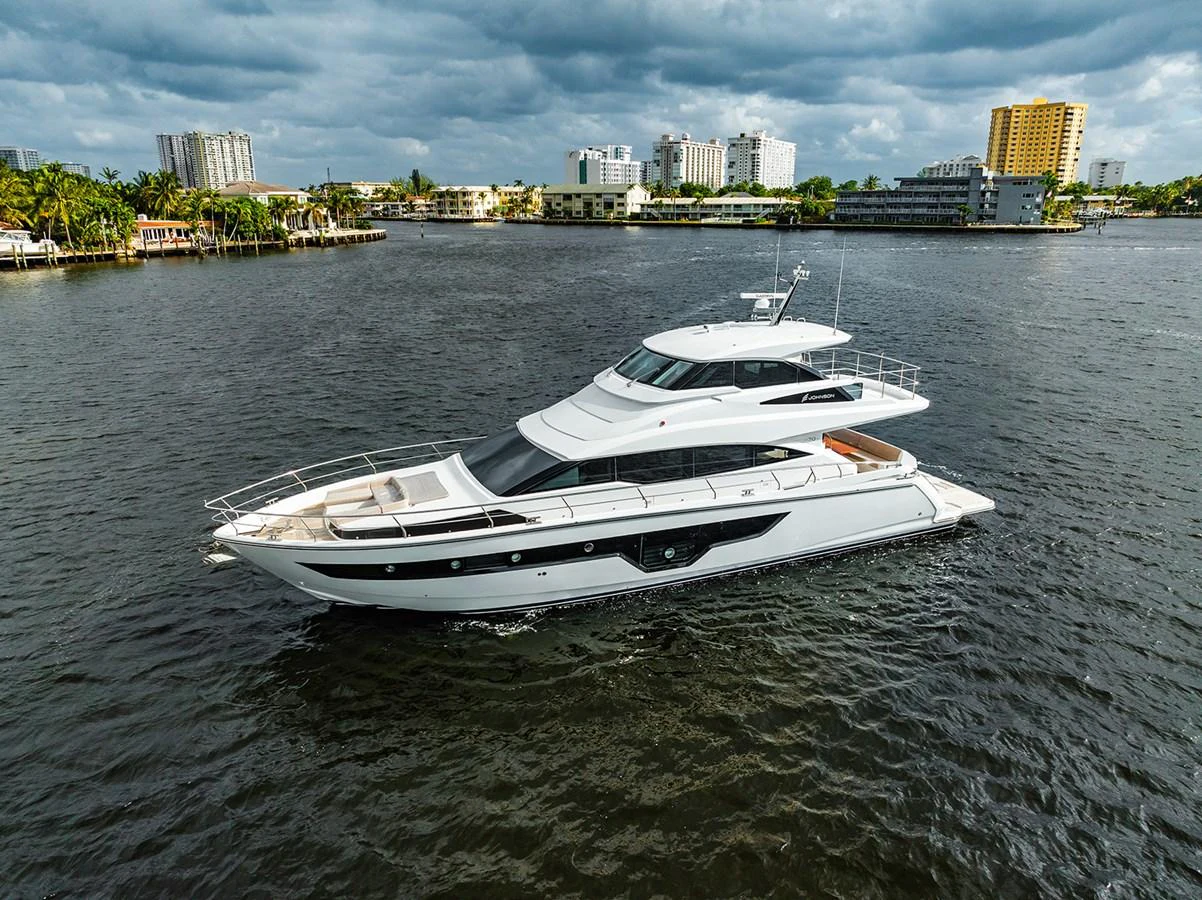 A sleek and modern yacht glides gracefully on the water with an urban skyline in the background. aboard INDIGO Yacht for Sale