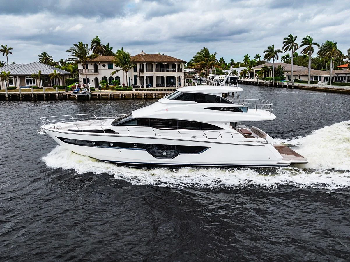 A sleek yacht cruises through a scenic waterway lined with luxurious homes and palm trees. aboard INDIGO Yacht for Sale