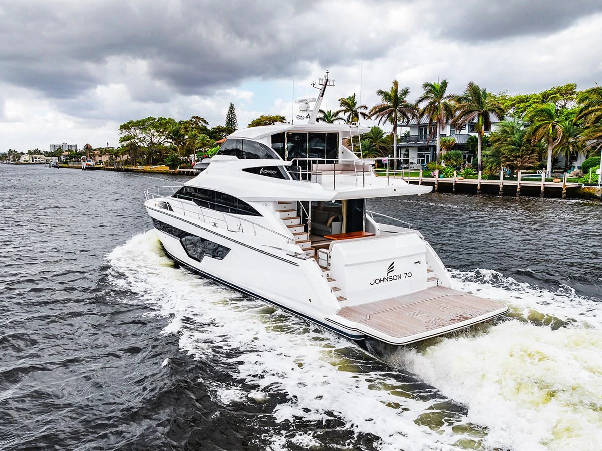 A sleek yacht cruises through a scenic waterway, showcasing its elegant design and spacious aft deck. aboard INDIGO Yacht for Sale