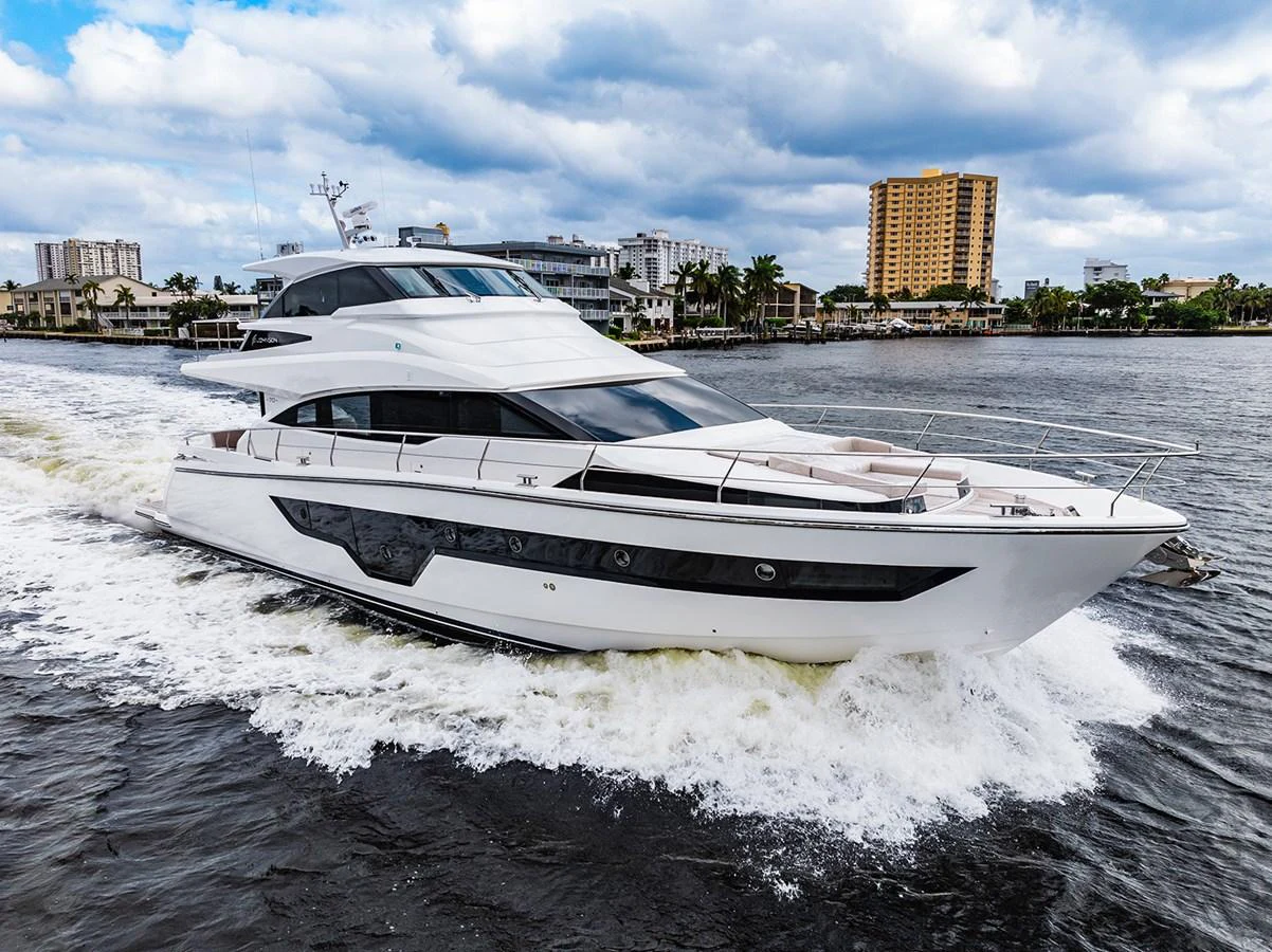 A sleek and modern yacht cruising through the water with an urban skyline in the background. aboard INDIGO Yacht for Sale