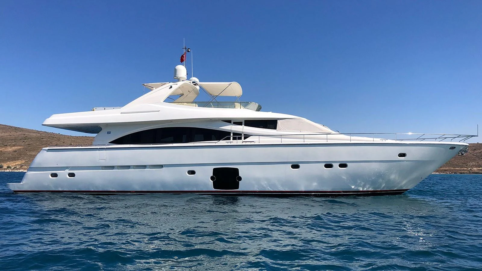 A sleek, modern yacht glides gracefully on calm blue waters under a clear sky. aboard QUIT Yacht for Sale