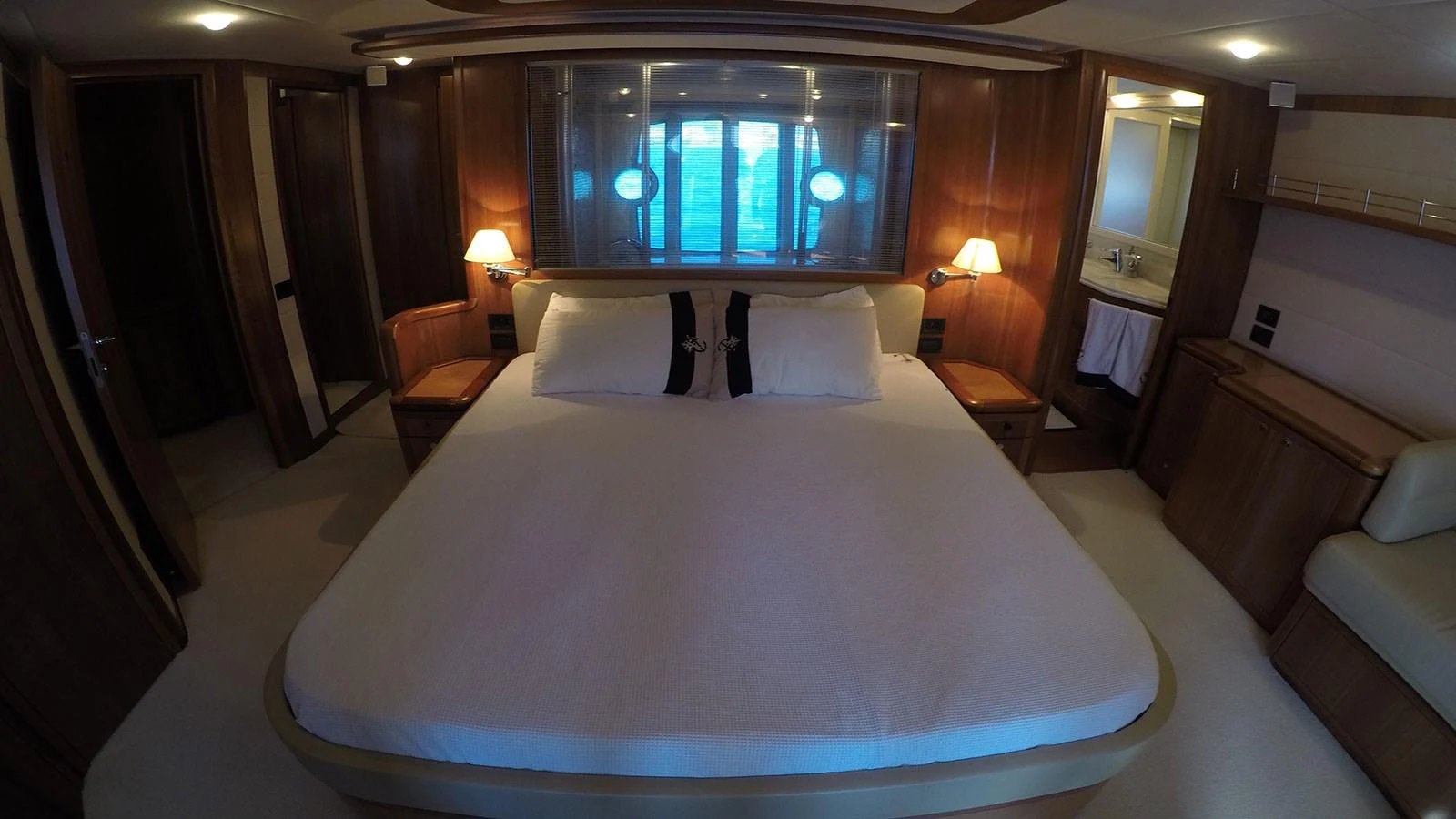The master stateroom features a spacious bed with elegant wood paneling and ambient lighting. aboard QUIT Yacht for Sale