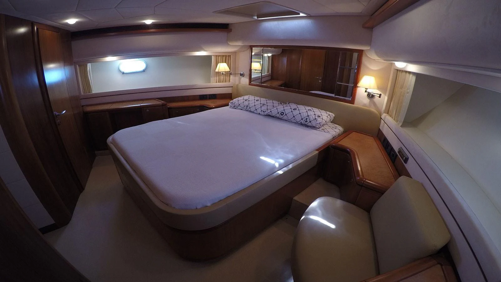 The stateroom features a comfortable bed with elegant wood finishes and ambient lighting. aboard QUIT Yacht for Sale