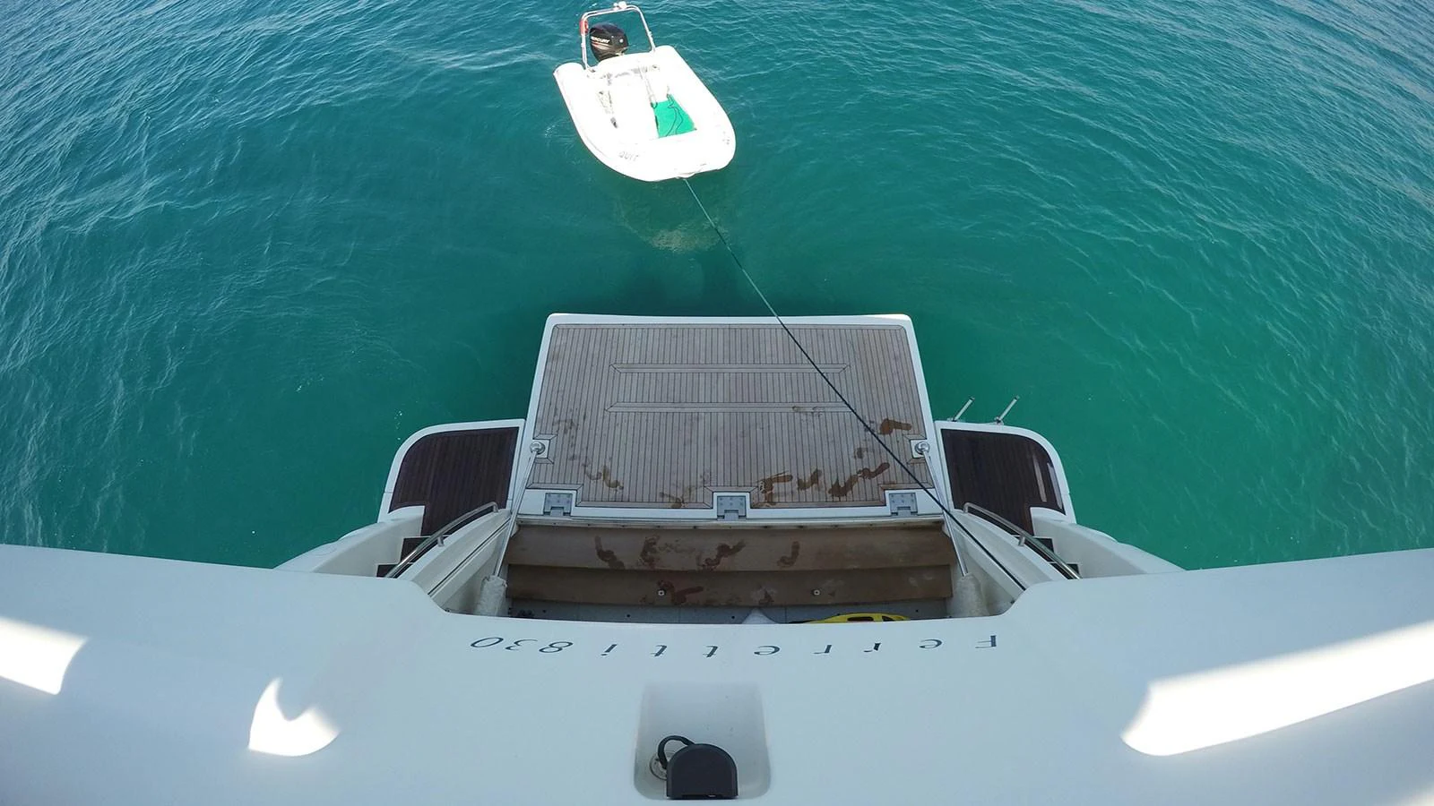 A tender is seen floating behind the yacht, tethered to the swim platform. aboard QUIT Yacht for Sale