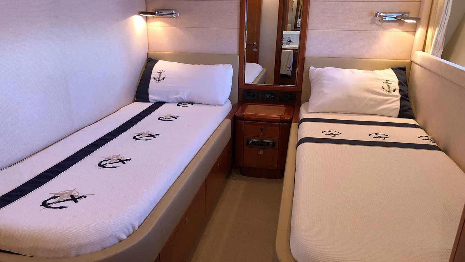 A cozy twin stateroom featuring nautical-themed bedding and warm lighting. aboard QUIT Yacht for Sale