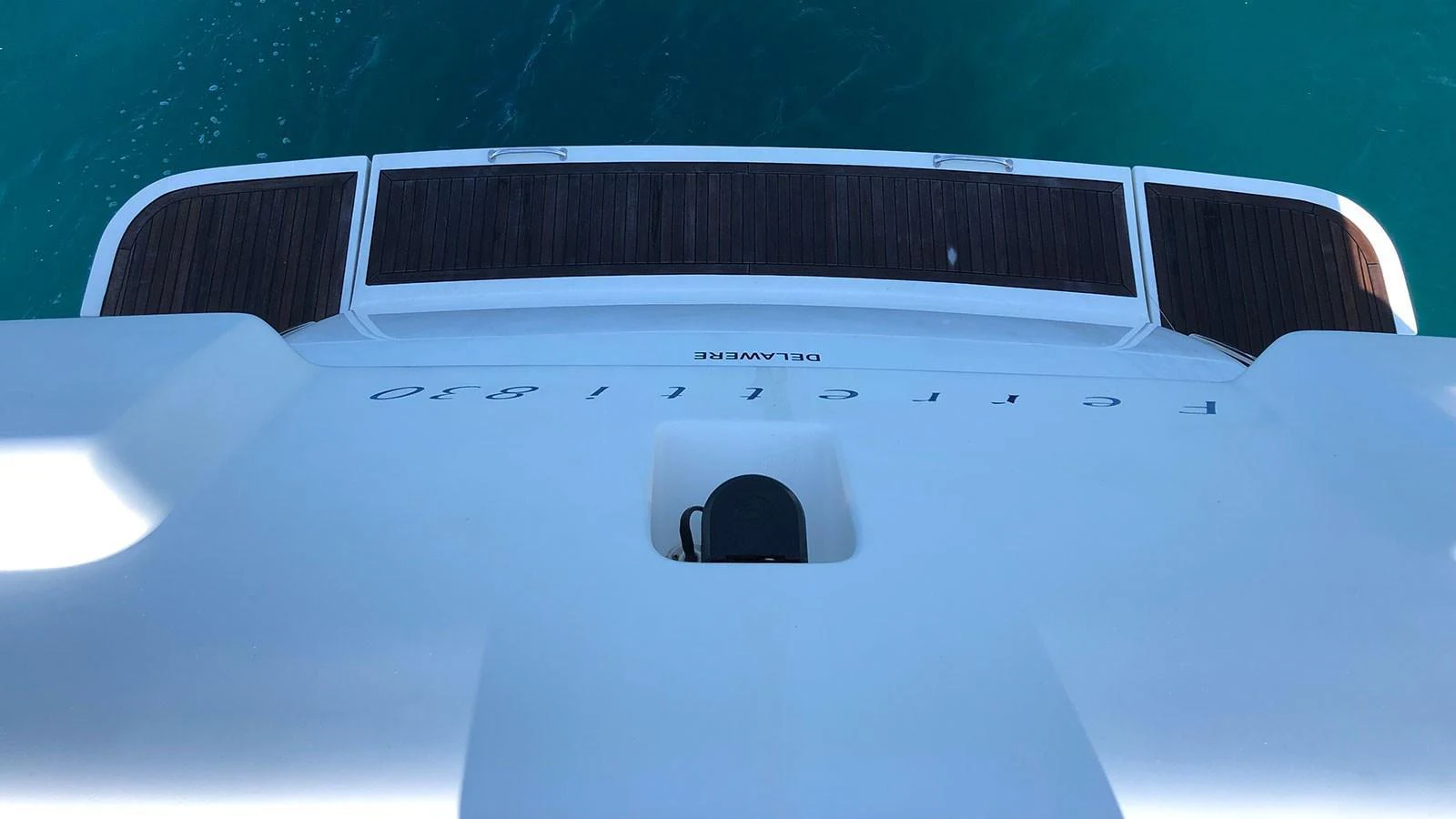 A detailed view of the yacht's stern platform with teak decking and clear water below. aboard QUIT Yacht for Sale