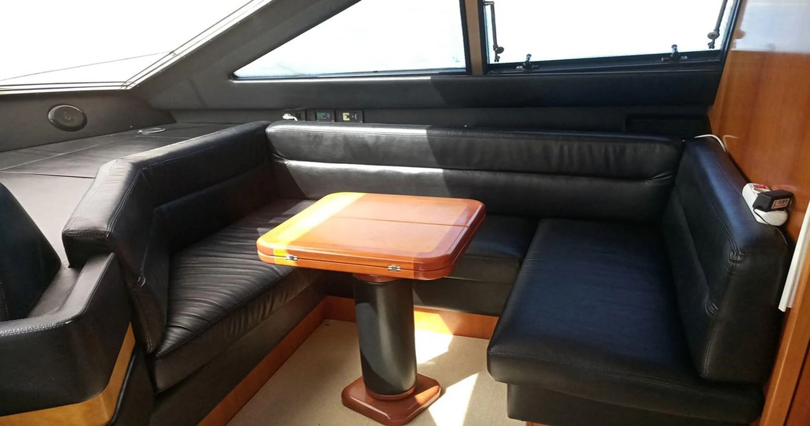 The yacht's saloon features a cozy seating area with a wooden table and black leather upholstery. aboard QUIT Yacht for Sale