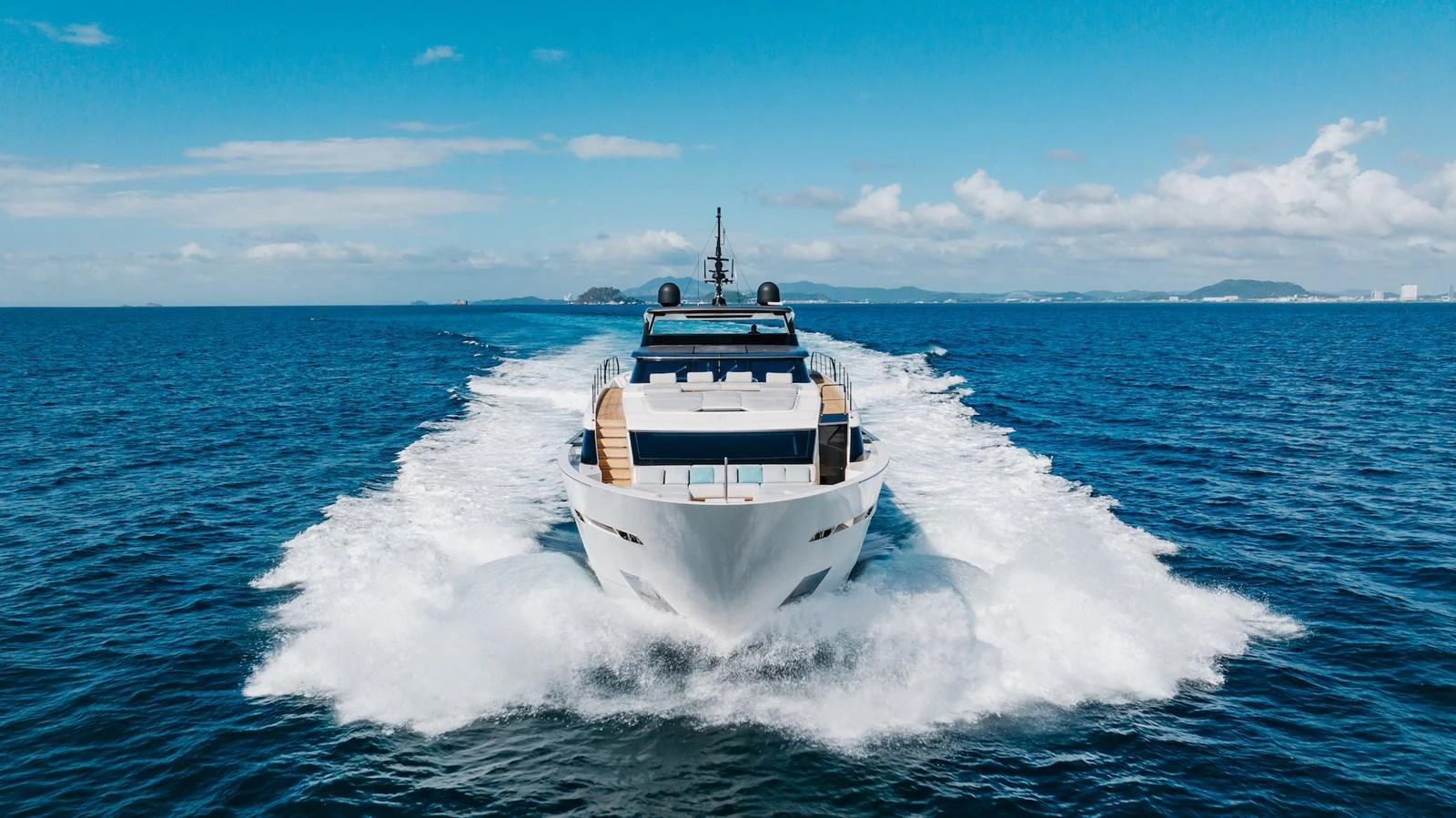 A sleek yacht cruises forward on open water under a bright blue sky. aboard AMBAR Yacht for Sale