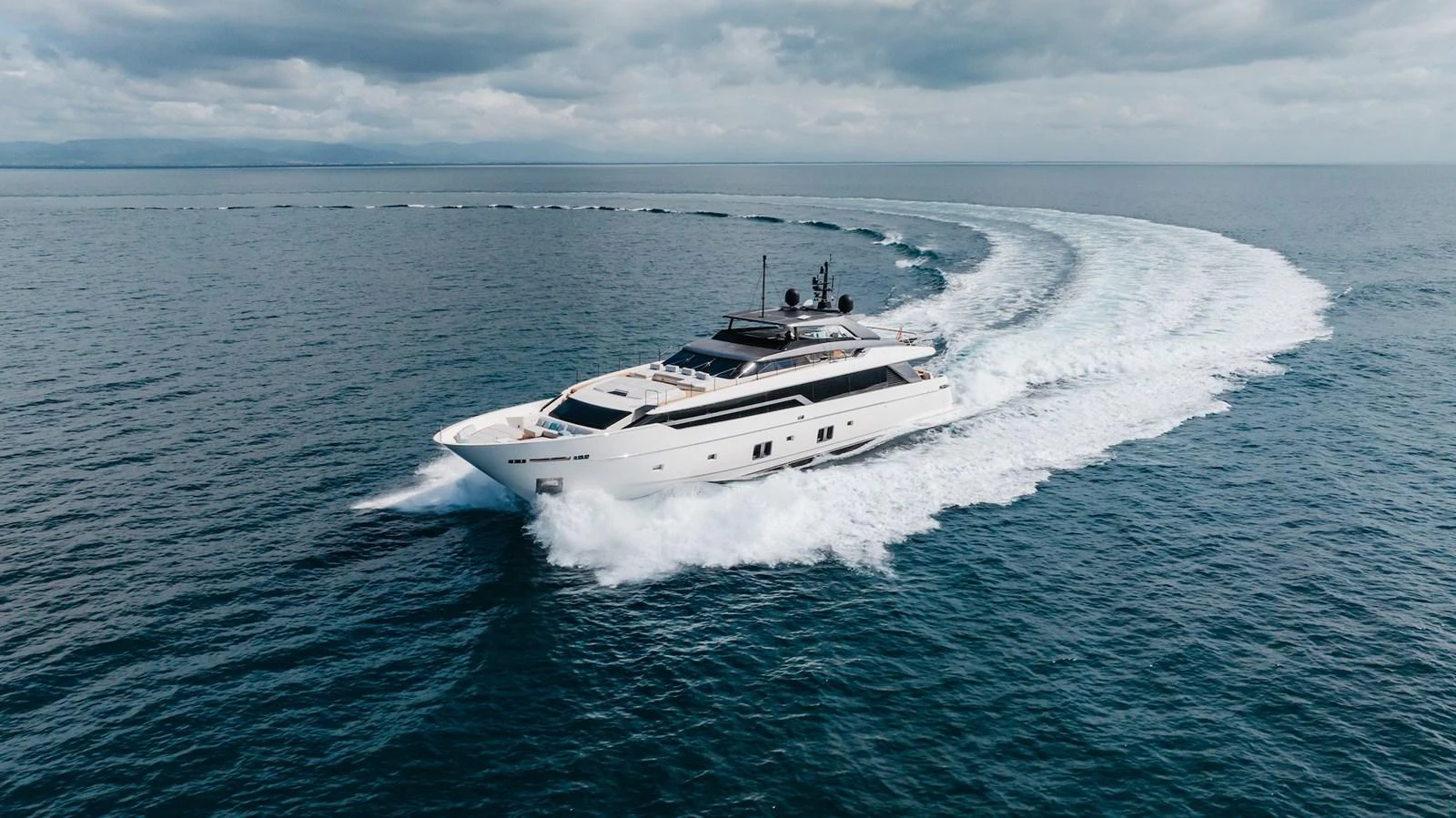A sleek and modern yacht cruises swiftly through open waters, leaving a trail of white foam behind. aboard AMBAR Yacht for Sale