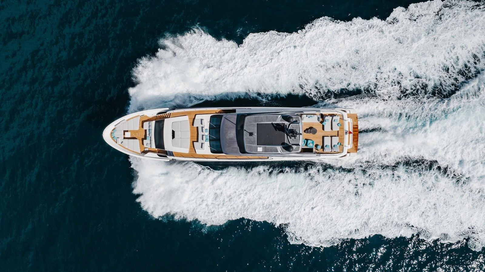A sleek yacht cruises swiftly through the water, showcasing its elegant design from an aerial perspective. aboard AMBAR Yacht for Sale