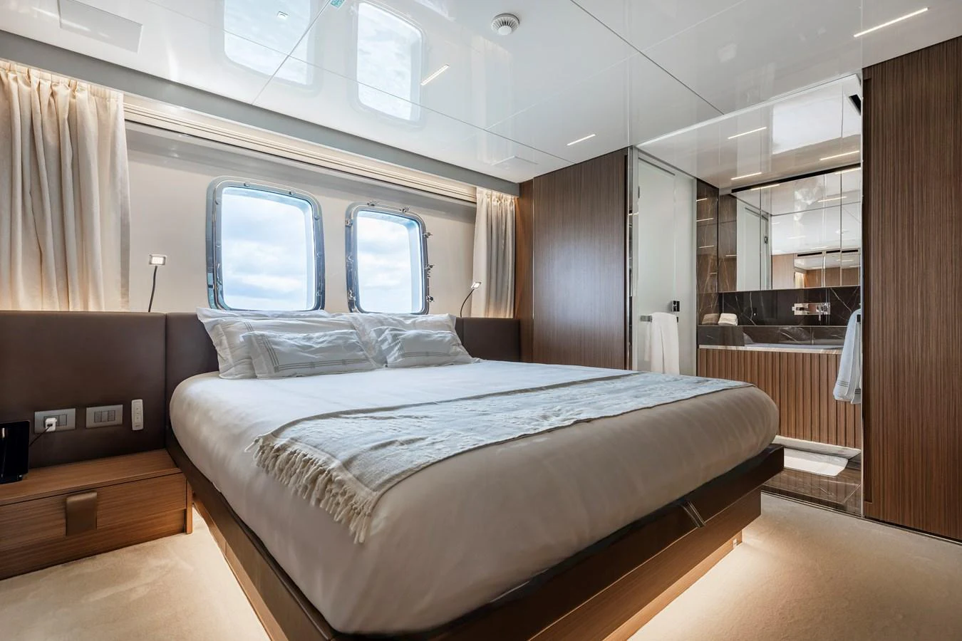 A luxurious stateroom with a large bed, wooden accents, and ample natural light from the windows. aboard AMBAR Yacht for Sale