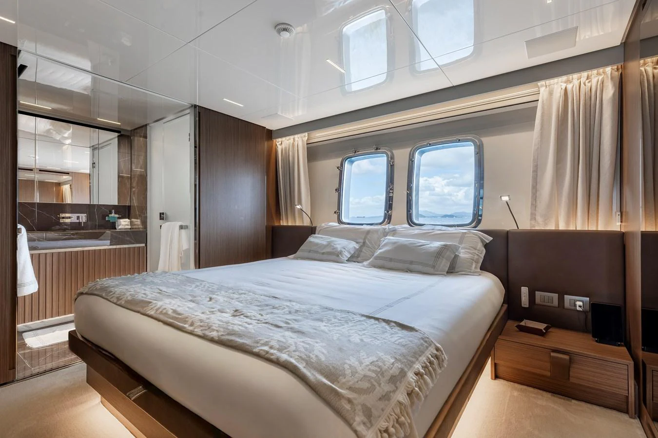 The stateroom features a luxurious bed with ample natural light from the windows. aboard AMBAR Yacht for Sale
