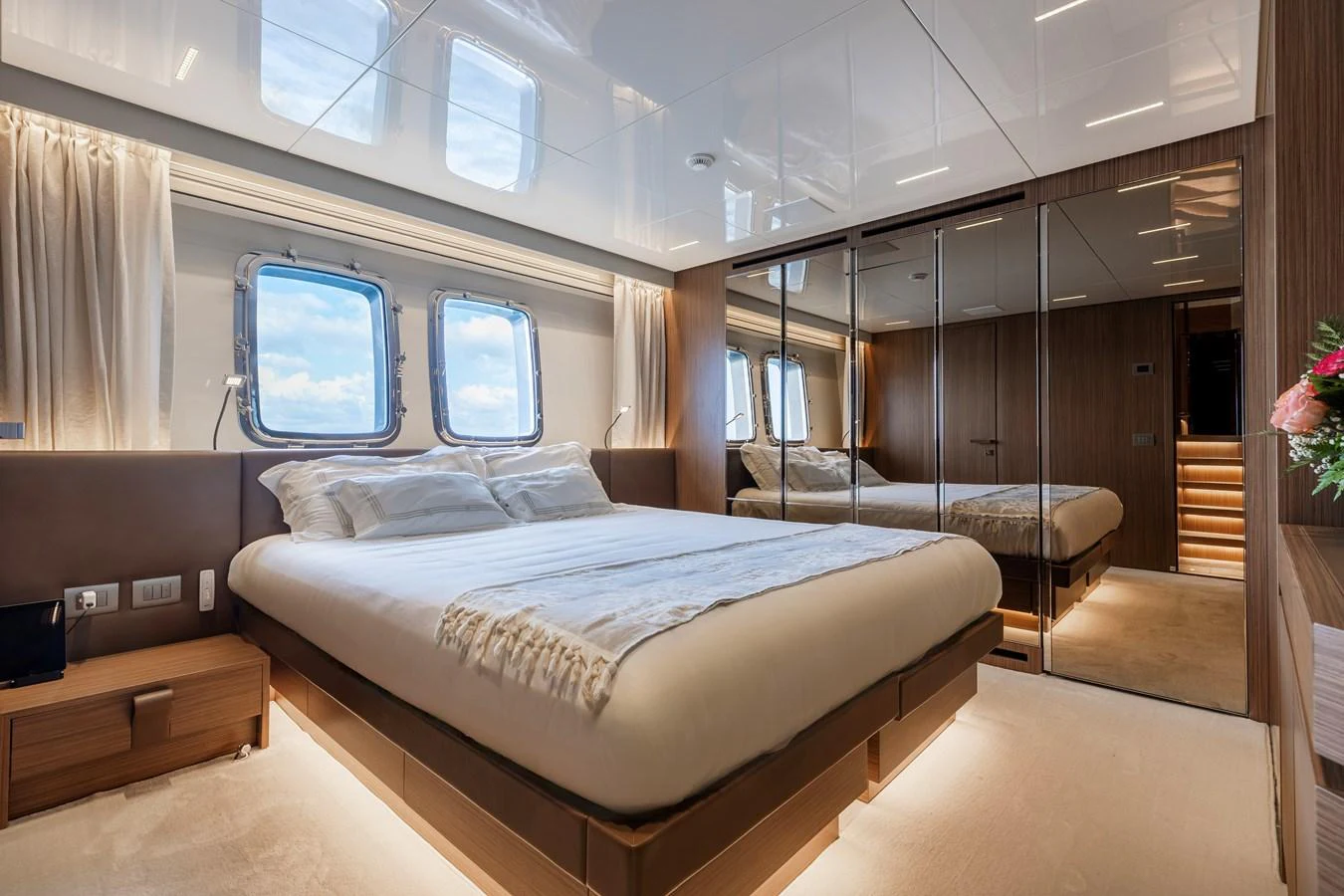 The stateroom features a luxurious bed with ample natural light from the large windows. aboard AMBAR Yacht for Sale