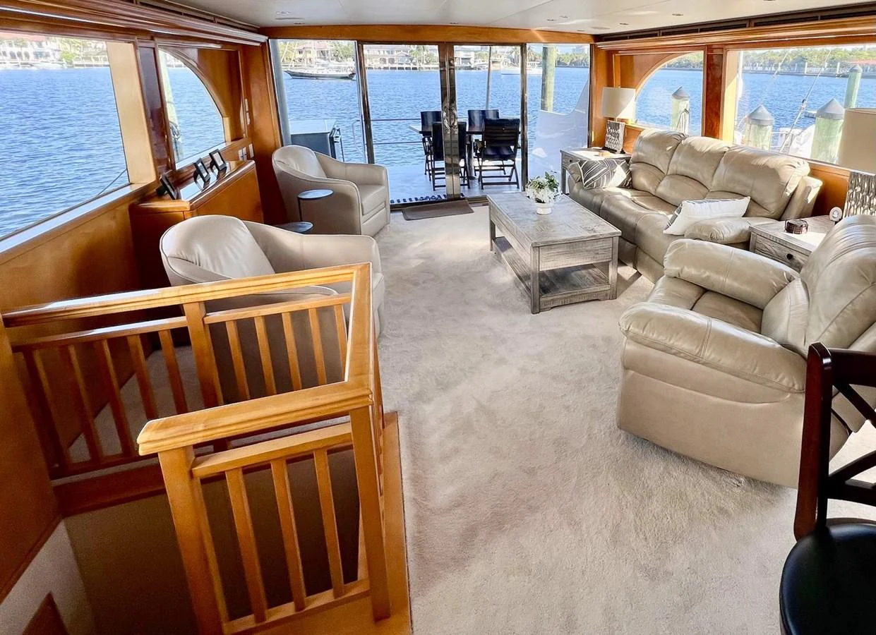 The salon features plush seating, a coffee table, and large windows offering stunning water views. aboard KRISTIN LEE Yacht for Sale