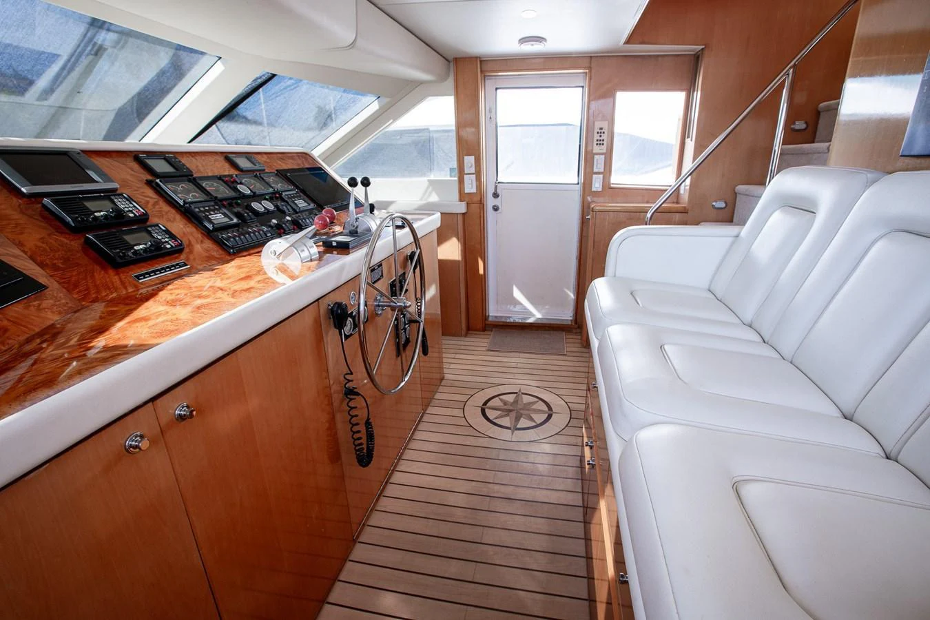 The helm station features a sleek wooden console with modern navigation equipment and comfortable seating. aboard KRISTIN LEE Yacht for Sale