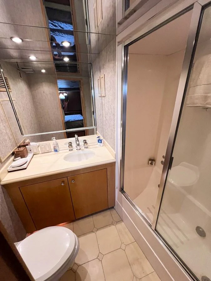 A well-appointed yacht bathroom featuring a shower, sink, and toilet with ample lighting and a mirror. aboard KRISTIN LEE Yacht for Sale