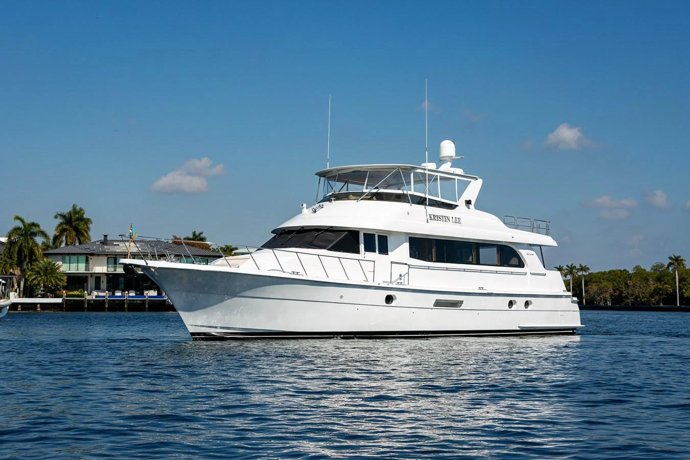 A sleek white yacht cruises gracefully on calm waters under a clear blue sky. aboard KRISTIN LEE Yacht for Sale