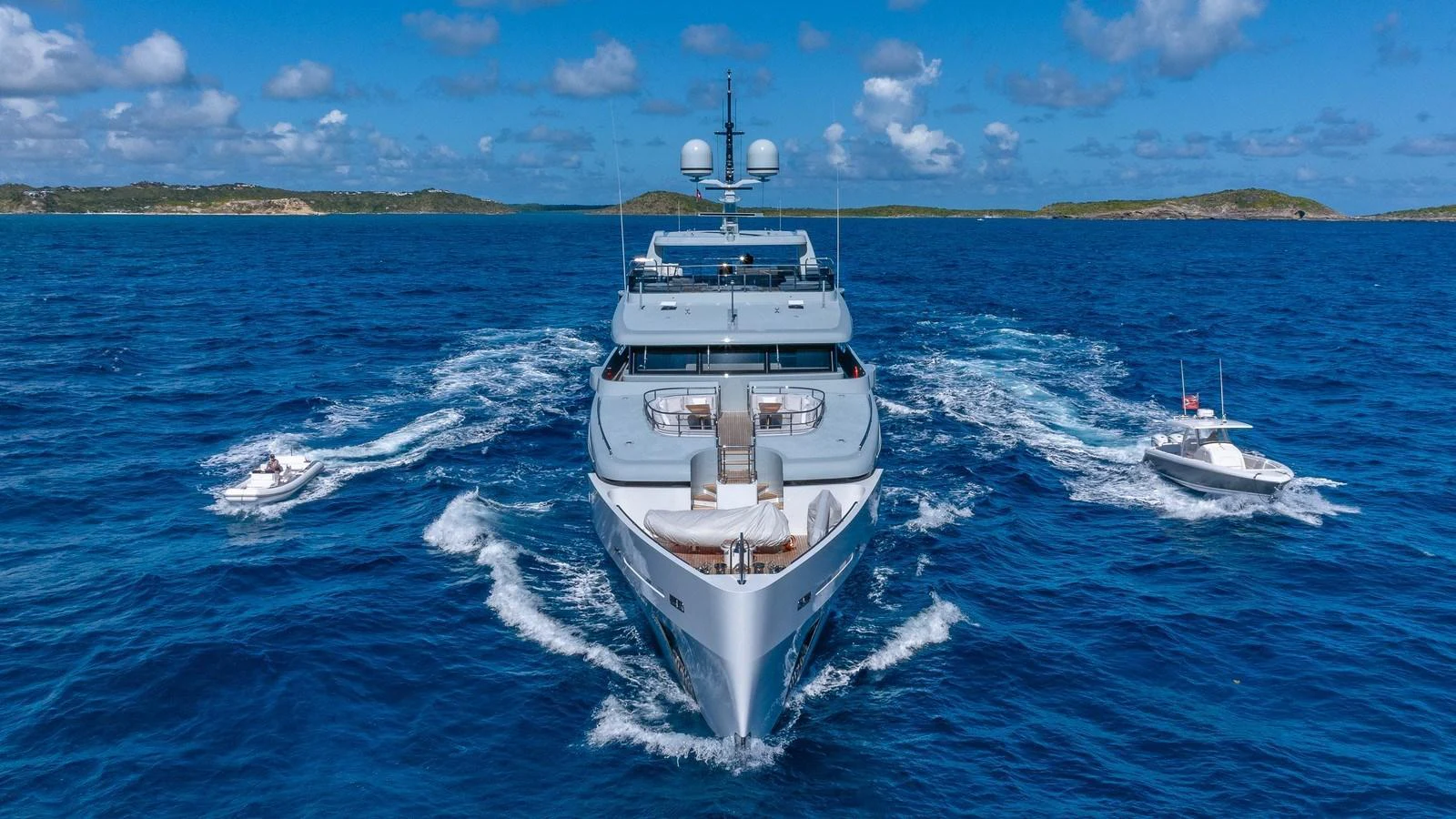 A luxurious yacht cruises through the open sea, accompanied by two smaller boats. aboard GIOIA Yacht for Sale