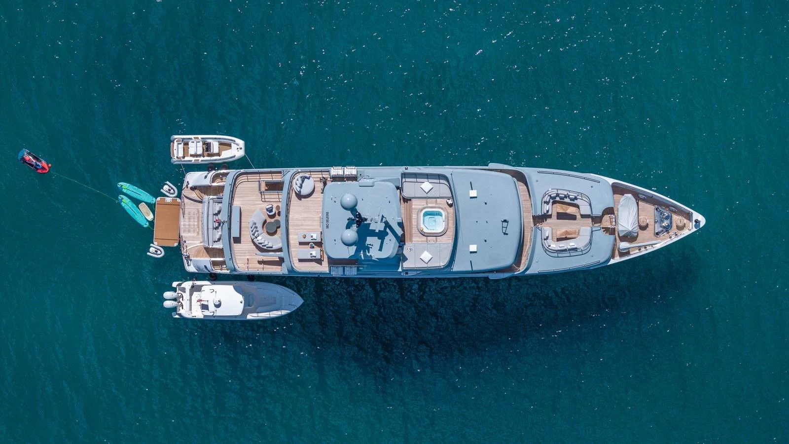 An aerial view of a luxurious yacht anchored in clear blue waters, showcasing its expansive deck and accompanying tenders. aboard GIOIA Yacht for Sale