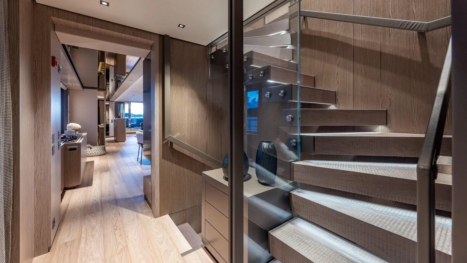 The yacht's interior features a modern staircase with sleek glass and wood elements, leading to a spacious and stylish living area. aboard GIOIA Yacht for Sale