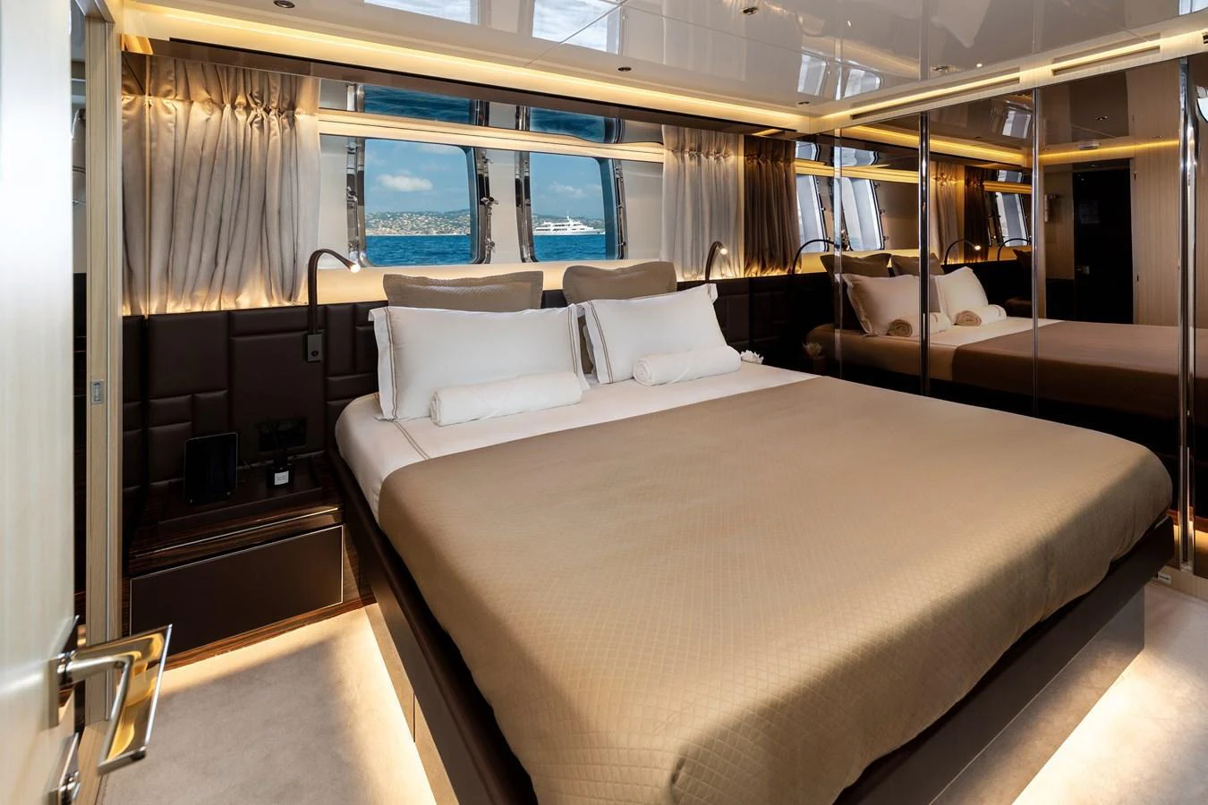 The master stateroom features a luxurious bed with elegant bedding and ample natural light from large windows. aboard NANGARA Yacht for Sale