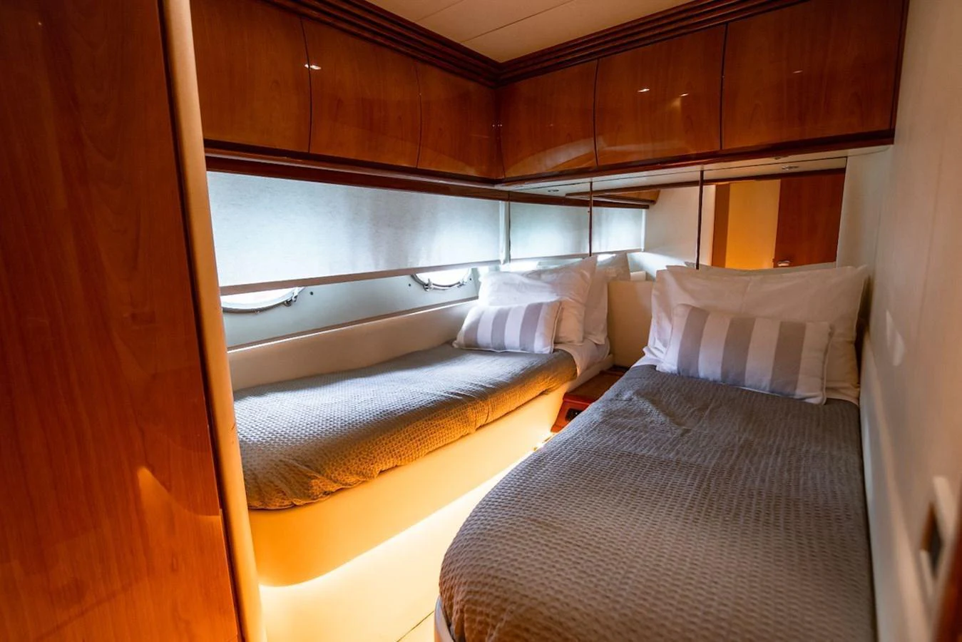 A cozy guest stateroom featuring twin beds with soft lighting and wooden cabinetry. aboard AXION Yacht for Sale