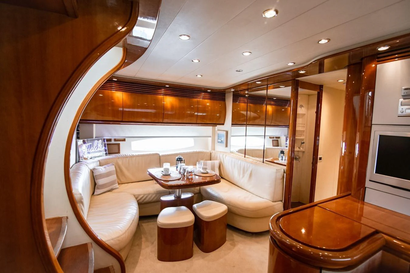 The yacht's salon features a cozy seating area with a wooden table and plush cushions, creating a warm and inviting atmosphere. aboard AXION Yacht for Sale