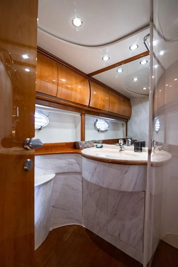 The yacht's bathroom features elegant wood paneling and a sleek marble countertop. aboard AXION Yacht for Sale
