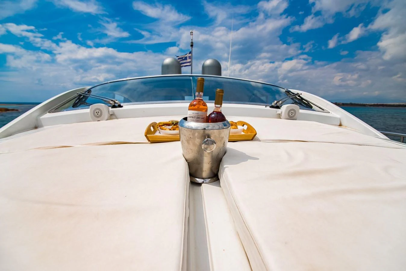 A luxurious setup with drinks on the deck of a yacht under a clear blue sky. aboard AXION Yacht for Sale