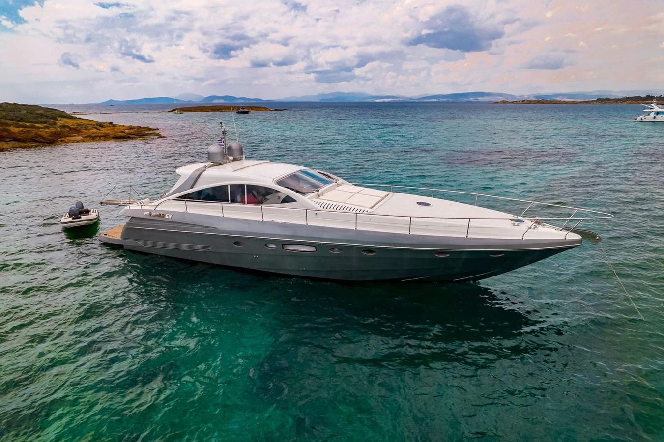 A sleek and modern yacht cruising in clear, turquoise waters with scenic islands in the background. aboard AXION Yacht for Sale