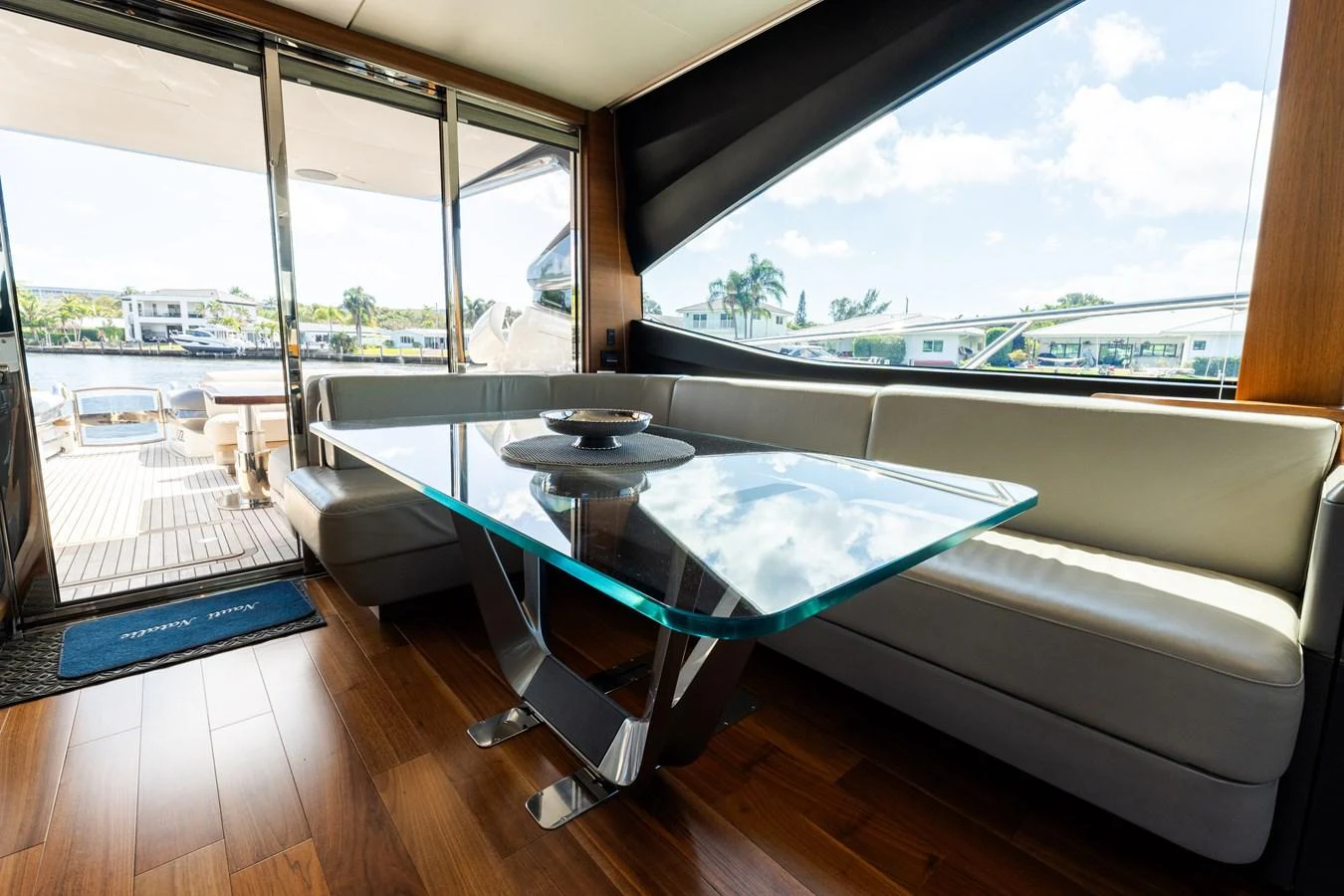 The salon features a sleek glass dining table with a comfortable L-shaped sofa, offering a stylish and inviting space for relaxation and dining. aboard NAUTI NATALIE Yacht for Sale