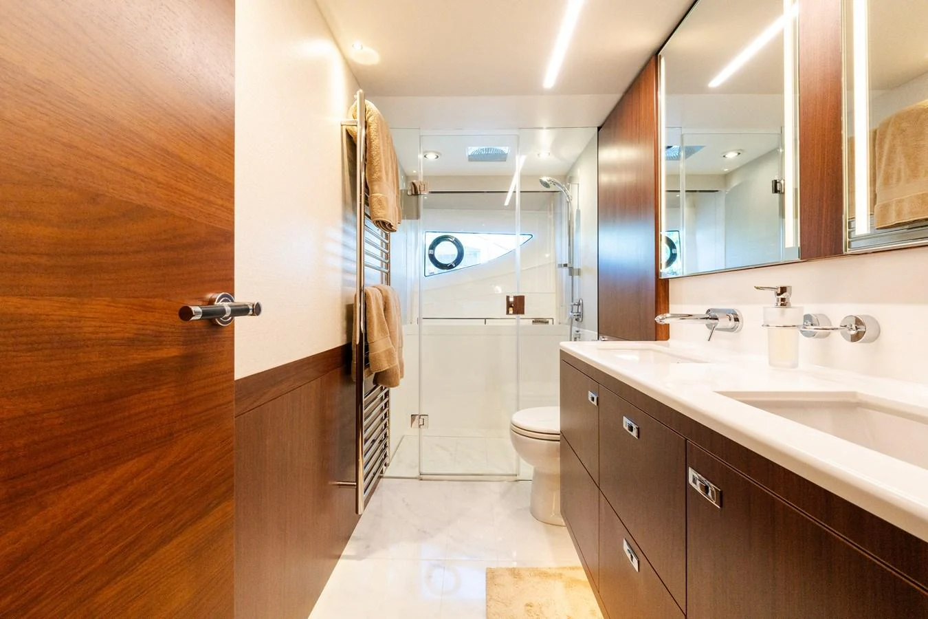 The yacht's bathroom features sleek wood paneling, a spacious vanity, and modern fixtures. aboard NAUTI NATALIE Yacht for Sale