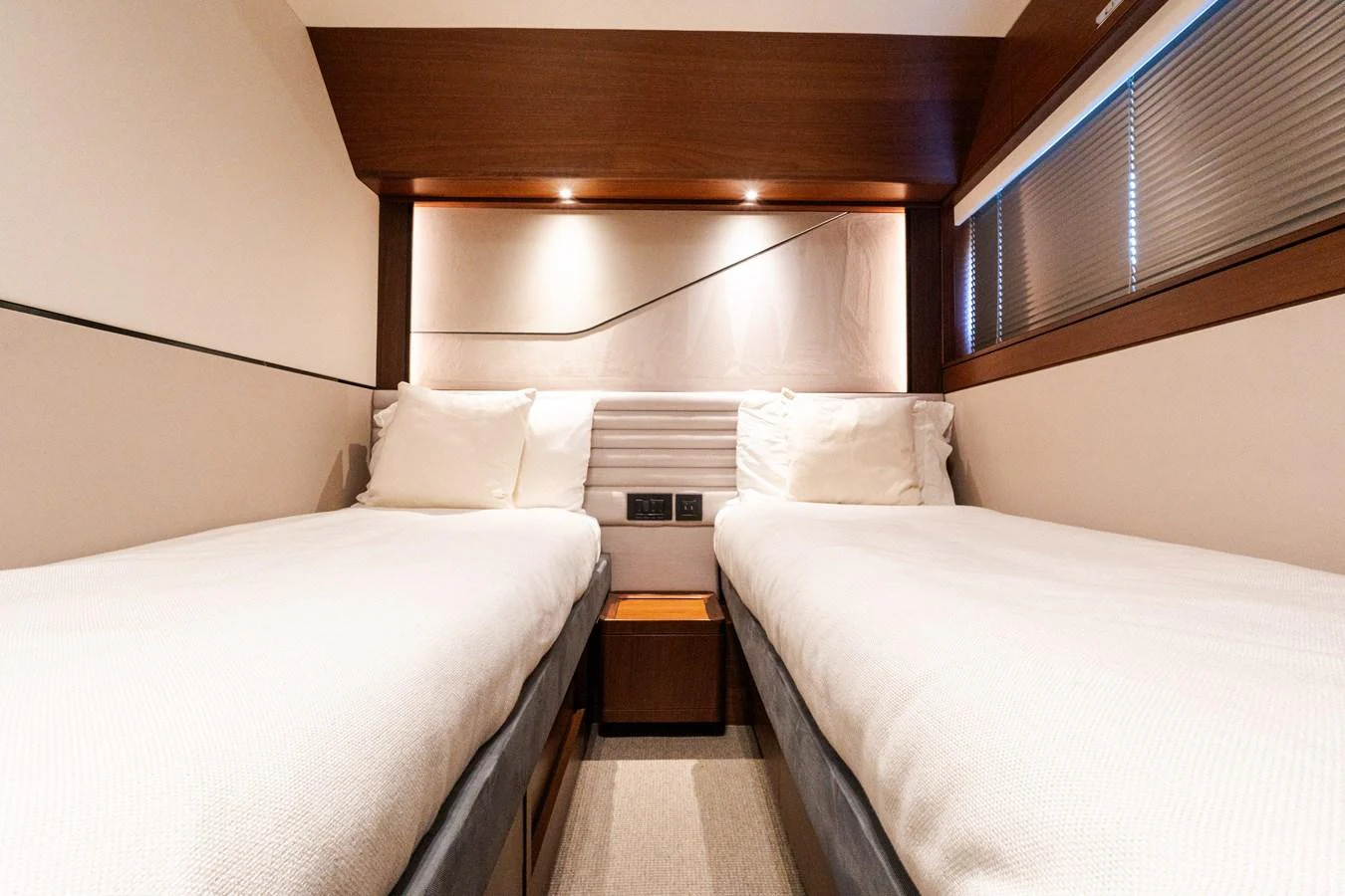 The twin stateroom offers a cozy and modern sleeping arrangement with two single beds and elegant lighting. aboard NAUTI NATALIE Yacht for Sale