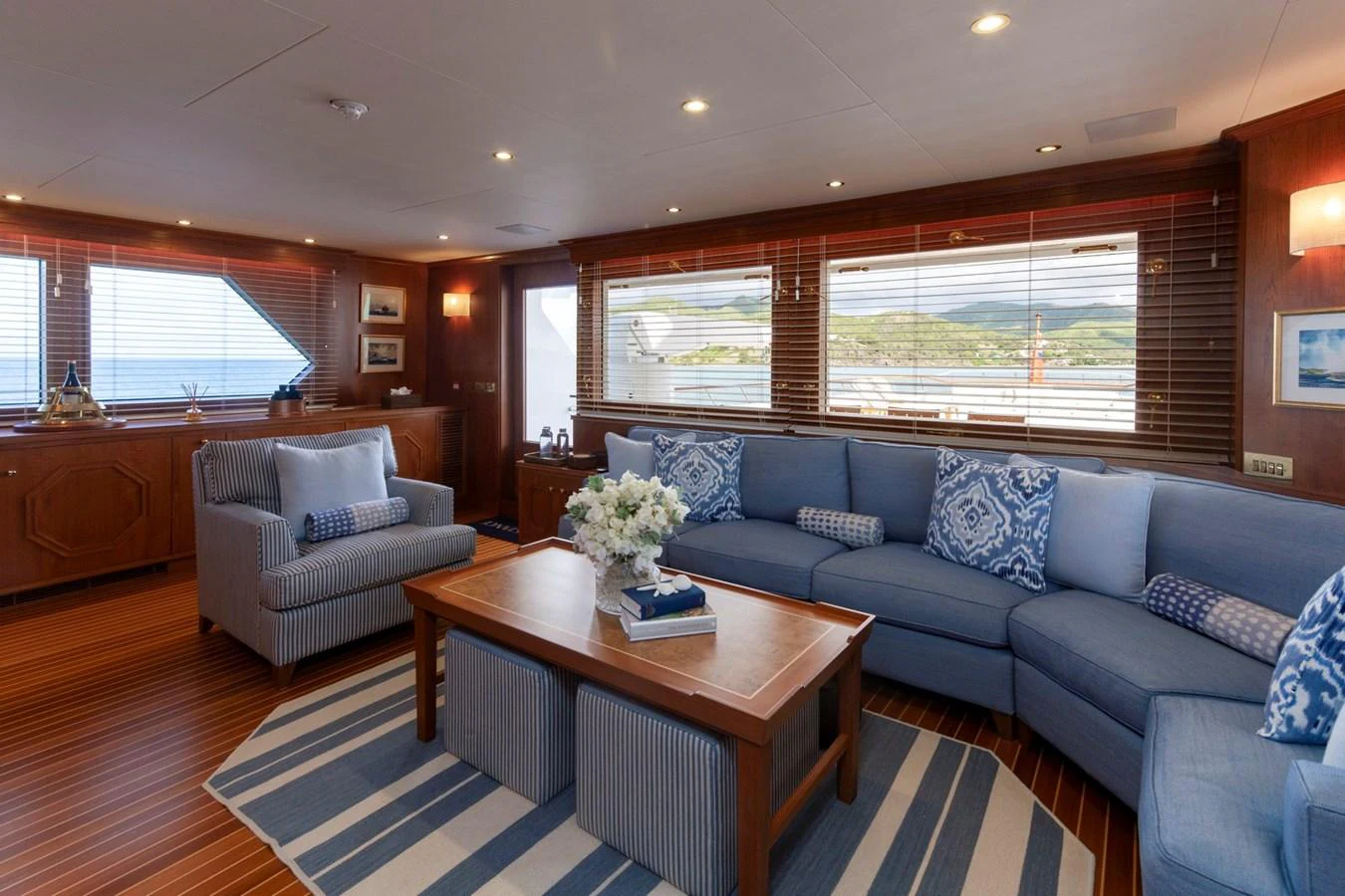 The salon features a spacious seating area with plush blue sofas and a wooden coffee table, creating a cozy and inviting atmosphere. aboard CONSTANCE Yacht for Sale