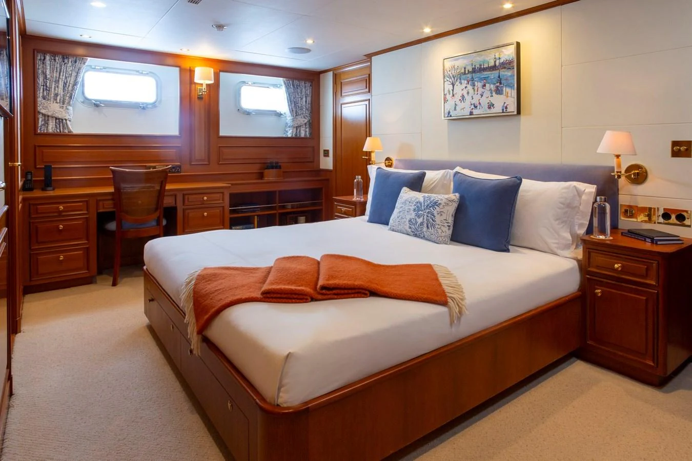 The stateroom features a plush bed, elegant wood paneling, and ample natural light from the windows. aboard CONSTANCE Yacht for Sale