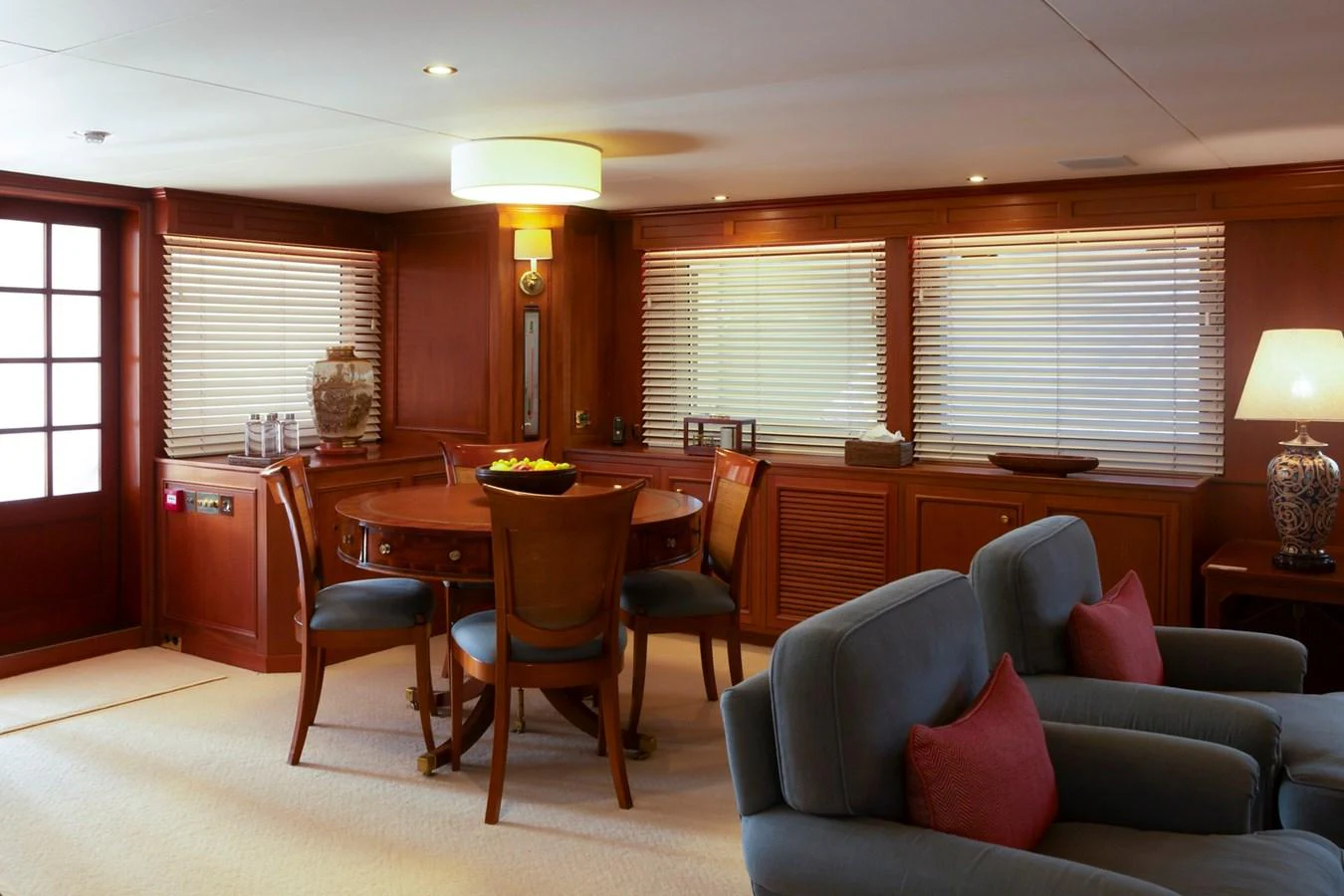 The yacht's salon features a cozy seating area with plush chairs and a dining table, creating a warm and inviting atmosphere. aboard CONSTANCE Yacht for Sale